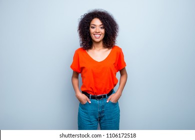 Portrait of joyful cute woman with modern hairdo in bright t-shirt jeans holding two hands in pockets isolated on grey background