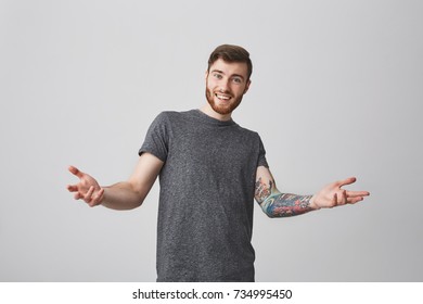 Portrait Of Joyful European Bearded Man With Stylish Hairstyle And Tattooed Arm Looking In Camera With Delight Expression, Spreading Arms Going To Hug Girlfriend.