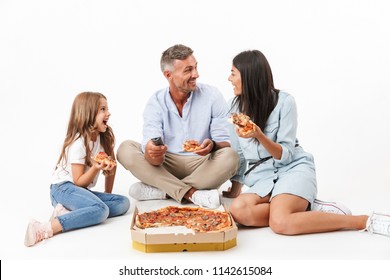 Portrait Of A Joyful Family Father, Mother, Little Daughter Having Fun While Eating Pizza And Watching TV Isolated Over Gray Background