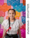 Portrait of a joyful girl in Mexican dress, colorful backdrop