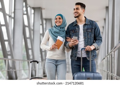 Portrait Of Joyful Islamic Spouses Standing With Luggage, Passports And Smartphone At Airport, Happy Muslim Couple, Arab Man And Woman In Hijab Travelling Abroad Together, Ready For Trip, Copy Space
