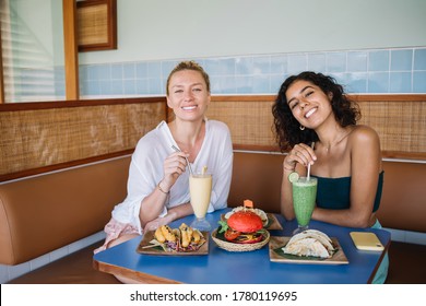 Portrait Of Joyful Multiracial Best Friends Smiling At Camera During Positive Meeting Split Mexican Lunch, Funny Female Customers Enjoying Tex Mex Food During Pastime For Taste Latin Cuisine