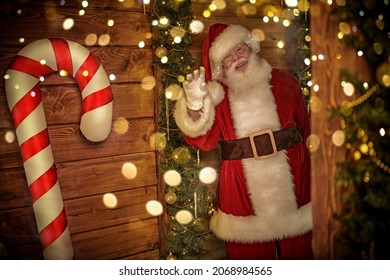 Portrait of a joyful smiling Santa Claus in a wooden house among Christmas lights and festive decorations. Merry Christmas and Happy New Year! - Powered by Shutterstock