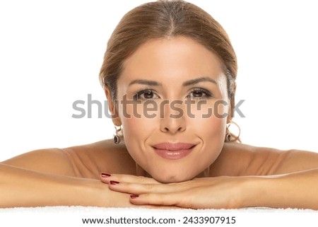 A portrait of a joyful woman with a beautiful smile and tasteful makeup,lying on white studio background, expressing happiness and confidence