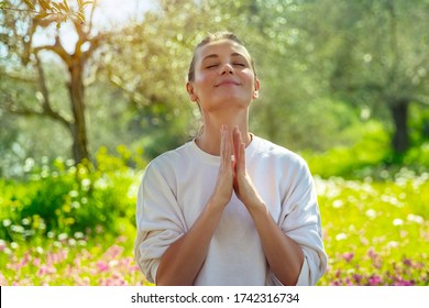 Portrait of a joyful woman with closed eyes meditating in a fresh blooming garden. Unity of a mind, body, and spirit. Calmness and peacefulness concept - Powered by Shutterstock