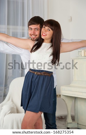 Portrait of a joyful young couple flying against home interior