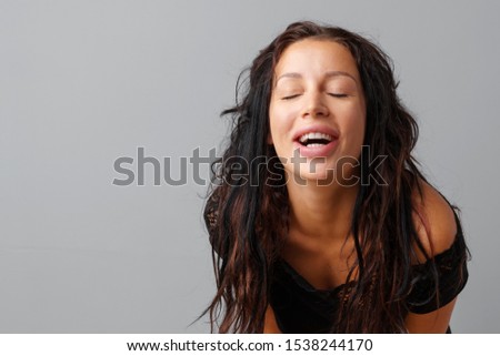 Portrait of joyful young cute woman laughing over a gray background