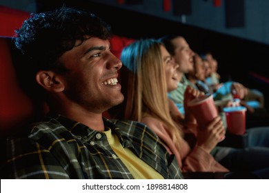 Portrait of joyful young guy smiling while watching movie together with friends in cinema auditorium. Entertainment and people concept. Horizontal shot. Side view - Powered by Shutterstock