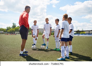 Portrait Of Junior Football Team Listening To Coach Giving Pep Talk Before Match