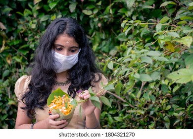 Portrait Of Kerala Girl Enjoying Onam Festival By Plucking Flowers In The Neighborhood During Corona Pandemic With Masks And Safety Measures.