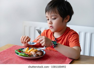 Portrait Of Kid With Bored Face Having Steak Salmon And Chips For Sunday Dinner At Home, Unhappy Child Eating Lunch, Children Eating Heathy And Fresh Food. Spoiled Child Concept