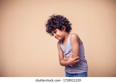 A Portrait Of Kid Boy With Curly Hair Feeling Strong Stomach Pain. Children, Medicine And Healthcare Concept