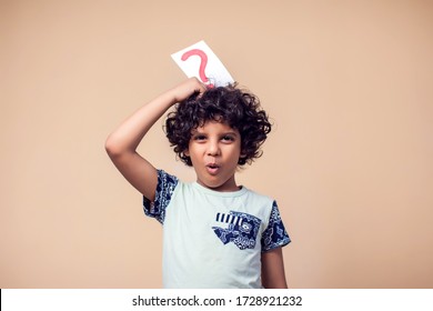 A Portrait Of Kid Boy Holding Cards With Question Mark. Childhood And Education Concept