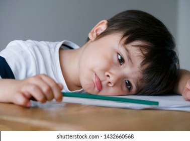 Portrait Kid Boy Holding Colour Pencil Sitting Alone And Looking Out With Bored Face,Preschool Child Laying Head Down On Table With Sad Face,Five Years Old Kid Bored With School Homework,spoiled Child