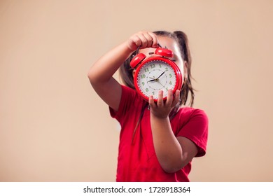 A Portrait Of Kid Boy Holding Red Alarm Clock. Childhood And Time Management Concept