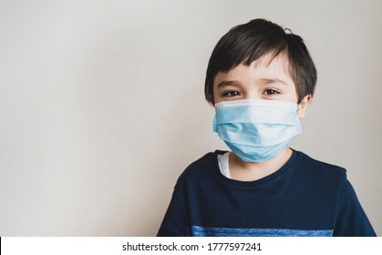 Portrait Kid Face Wearing Medical Face Mask, Mixed Race Child Boy With Beautiful Brown Eyeswearing Blue Face Mask Looking At Camera, Little Boy Stay At Home During Covid-19 Lock Down.