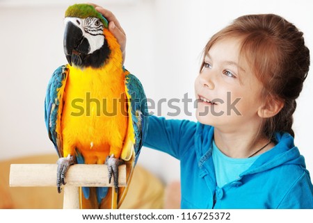 Portrait of a kid girl with her domestic ara parrot
