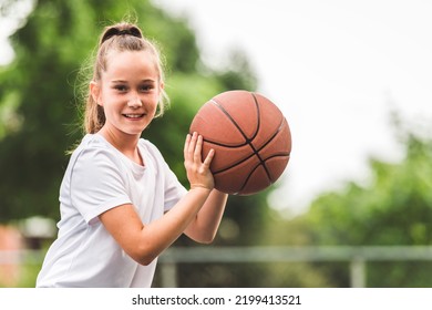 A Portrait Of A Kid Girl Playing With A Basketball In Park