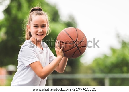 A portrait of a kid girl playing with a basketball in park