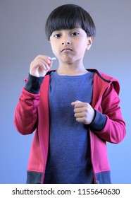 Portrait Of Kid Looking At Pill In Hand. Concept Of Unhappy Kid Or Child In Doubt Or Not Sure About Taking Medicine Or Vitamins.