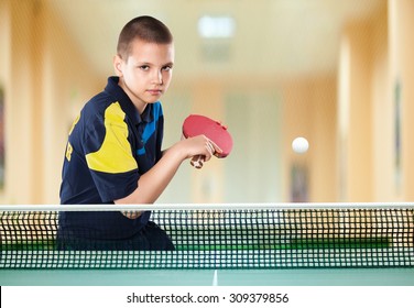 Portrait Of Kid With Racket Playing Table Tennis In Action Shot