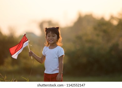 Portrait Of Kids Raising Indonesian Flag In Sunset Sky