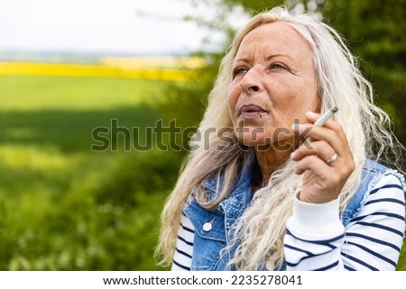 Portrait from a Lady smoking outdoor a cigarette.