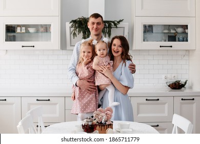 Portrait Of A Large Beautiful Family At The Table In The Kitchen. Mom Dad And 2 Daughters. High Quality Photo