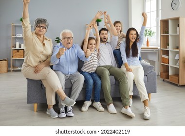 Portrait of a large family of different generations who are emotionally watching a sports match on TV at home. Grandparents with their children and grandchildren cheering while sitting on the sofa.