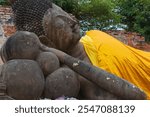 Portrait of large reclining Buddha stone statue in golden robe at Wat Yai Chai Mongkol at Ayutthaya, Thailand