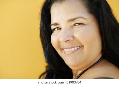 Portrait Of Latin American 50 Years Old Overweight Woman Smiling On Yellow Background. Head And Shoulders, Copy Space