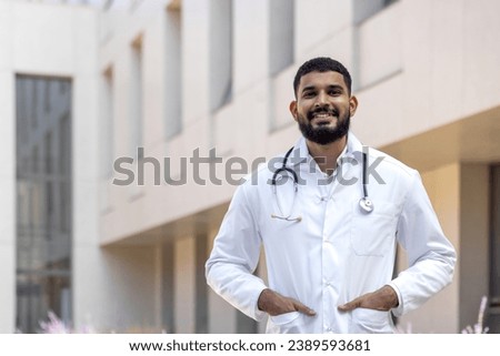Portrait of a Latin American male doctor, nurse, veterinarian standing outside the clinic on the street in a white coat and smiling and confidently looking at the camera.