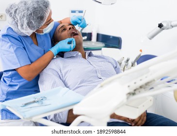 Portrait Of Latin American Man Sitting With Open Mouth During Dental Checkup At Dentist