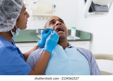 Portrait Of Latin American Man Sitting With Open Mouth During Dental Checkup At Dentist