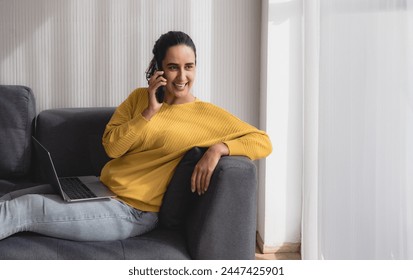 Portrait latin business freelance woman oneperson smile cheeful happy sitting sofa and look laptop talking mobile phone plan online job work newproject along with success future in living room office 