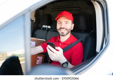 Portrait of a latin man in his 30s working and driving a delivery van. Happy male courier smiling while using the navigation map in his smartphone  - Powered by Shutterstock