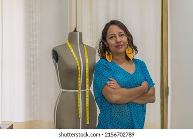Portrait of a latin seamstress posing next to a mannequin