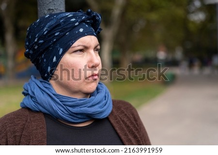 Portrait of a Latin woman undergoing cancer treatment with her head covered by a scarf with an expression of strength