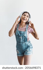 Portrait Of Latin Young Smiling Woman With Headphones, Dancing And Listening Music On A White Background In Latin America