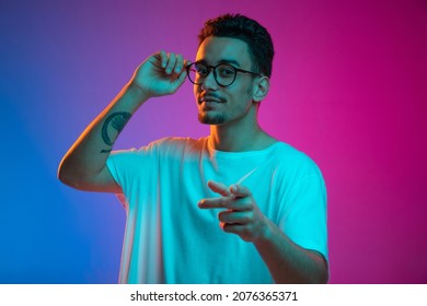Portrait Latina young man posing isolated gradient purple pink background in neon light  Beautiful male model in casual style  Concept human emotions  facial expression  youth  sales  ad 