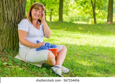 Portrait Laughing 50 Year Old Woman In The Park Dedicated To Knitting