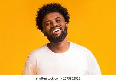 Portrait of laughing afro man over orange background, life is good