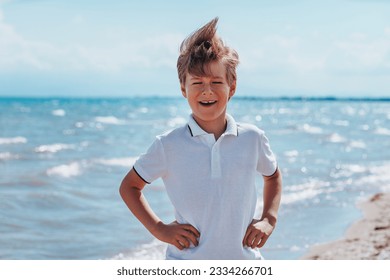 Portrait of laughing boy at the seaside in windy weather