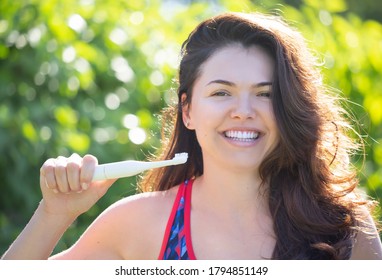 Portrait of a laughing brunette with white teeth and a toothbrush in hand