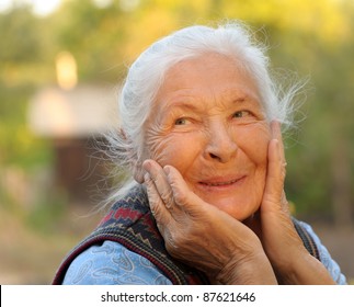 Portrait of the laughing elderly woman. A photo on outdoors