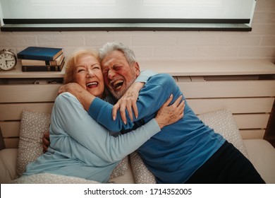 Portrait Of Laughing Embraced Couple. Elderly Couple Is Laughing While Lying In Bed In The Morning.