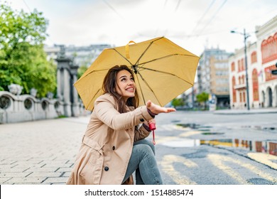 Portrait Of Laughing Happy Woman Under An Umbrella Near The City Centre. It's Spring Rain. Attractive Young Woman In The Street Under The Rain. I Make The Rain Look Good 