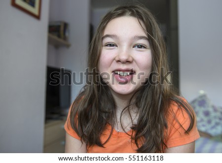 Portrait of laughing long-haired teen girl in the interior of her room.
