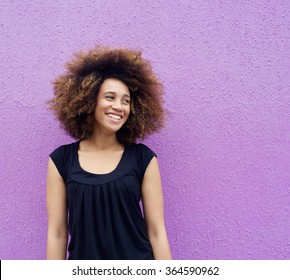 Portrait Of Laughing Young Woman Standing Against Purple Background