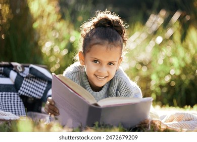 Portrait, learning and girl in a garden with book for reading, picnic and child development in nature. Smile, fantasy or happy kid with fairytale, story and literacy for studying, education or hobby - Powered by Shutterstock